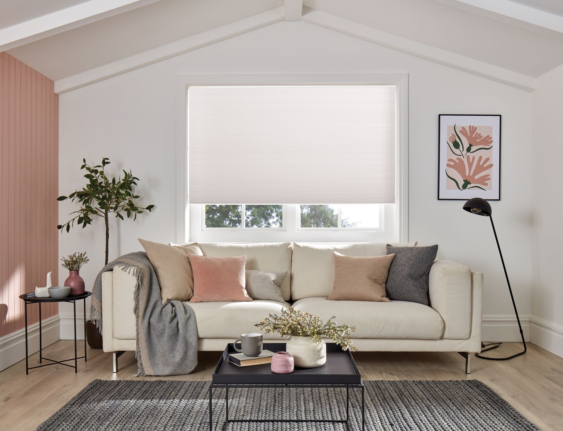 A living room with a couch , coffee table , rug and window.