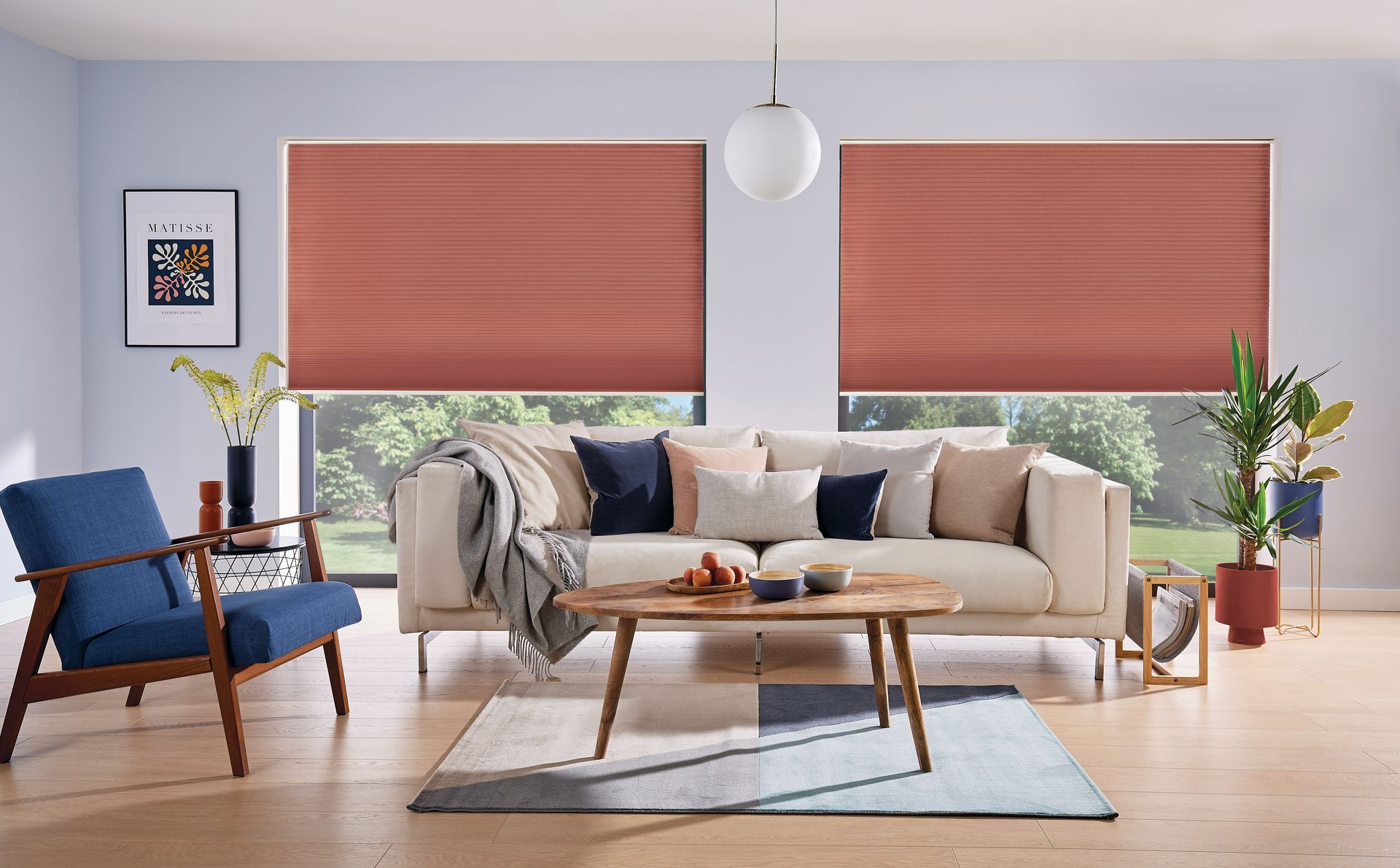 A living room with a couch , chair , coffee table and red blinds.