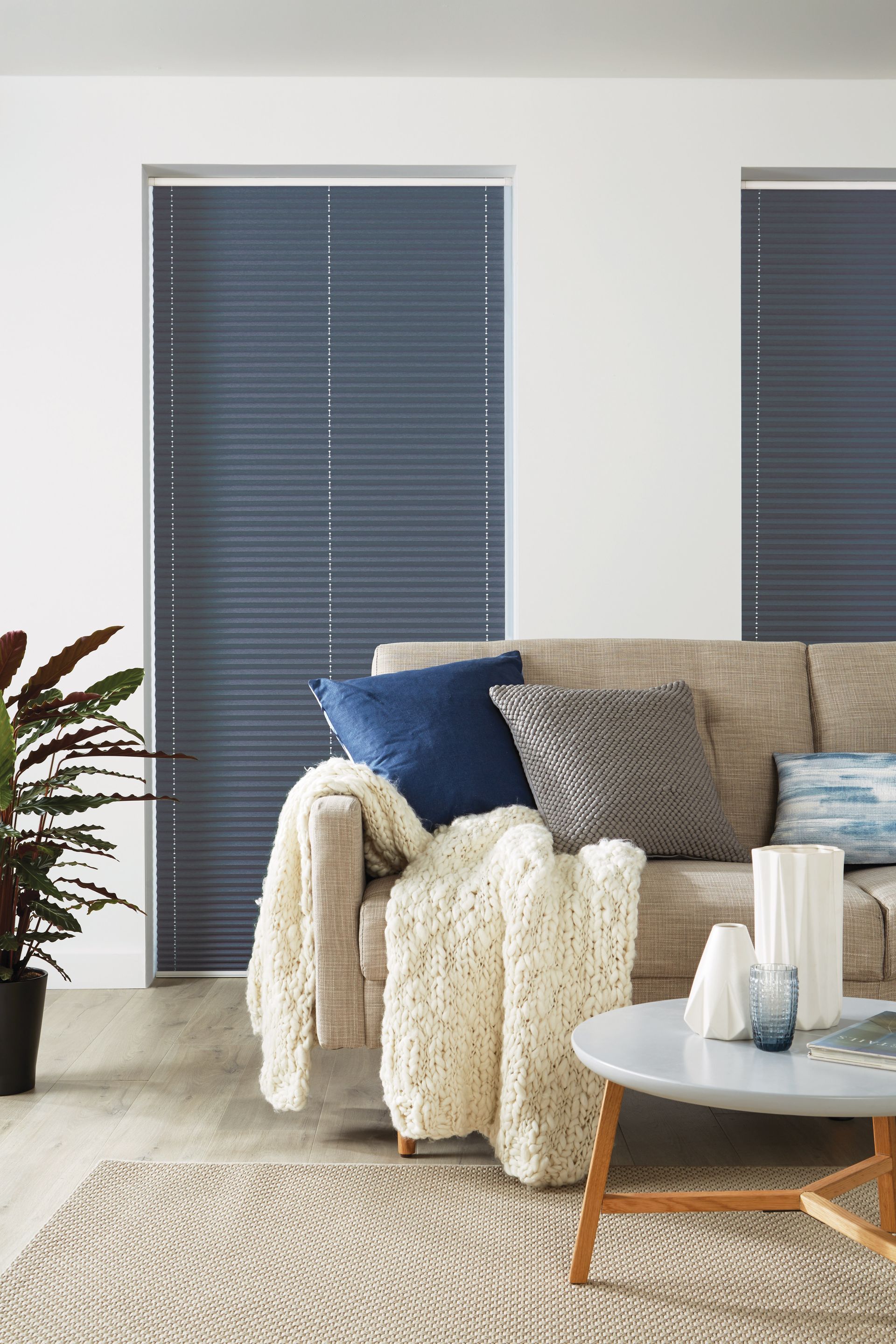 A living room with a couch , table , and blue blinds.