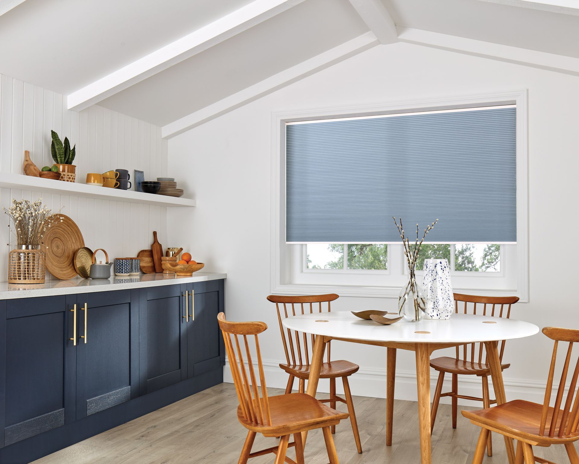 A kitchen with a table and chairs and a window with blinds.