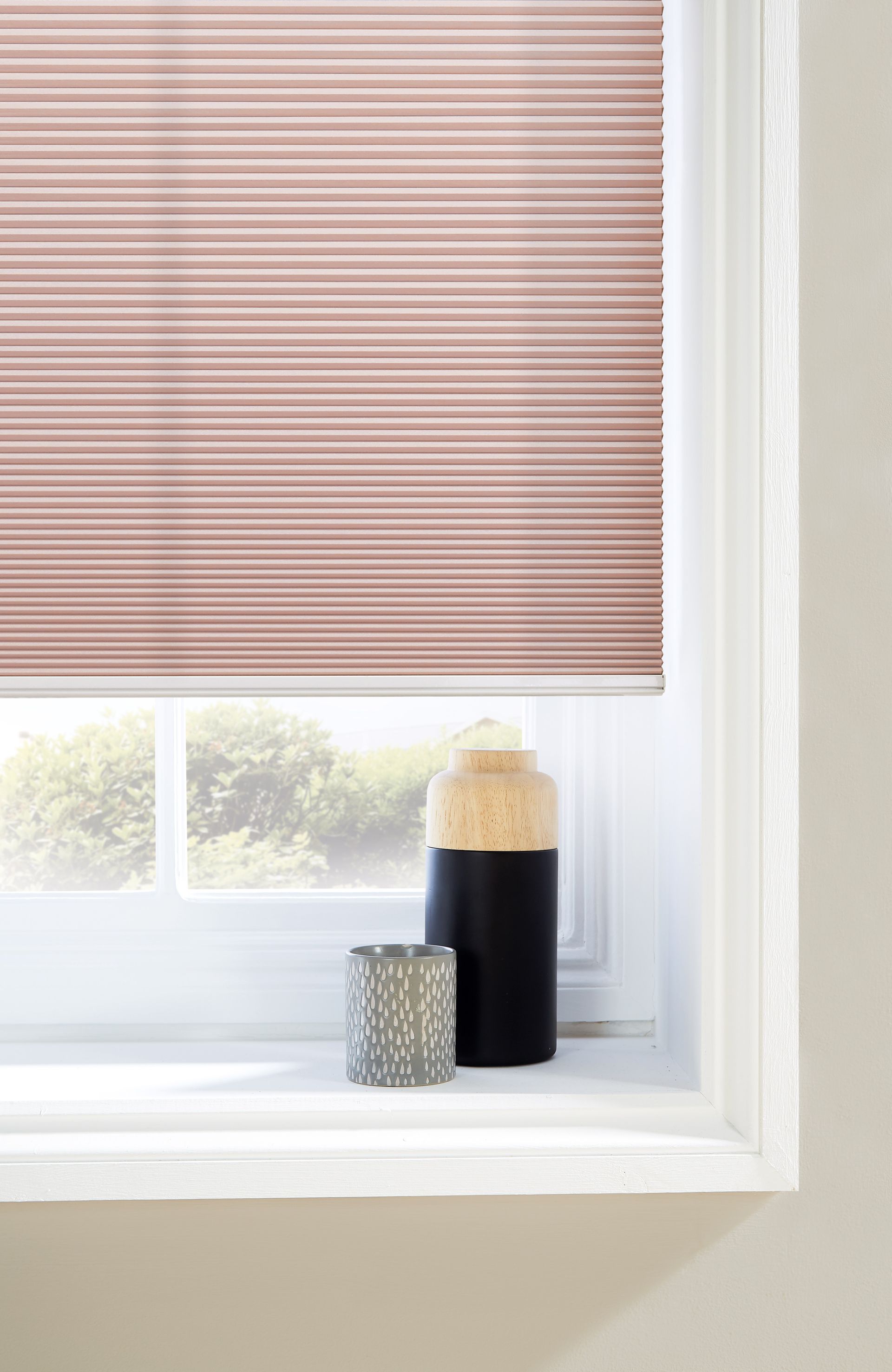 A window with a blind on it and a vase on the window sill.