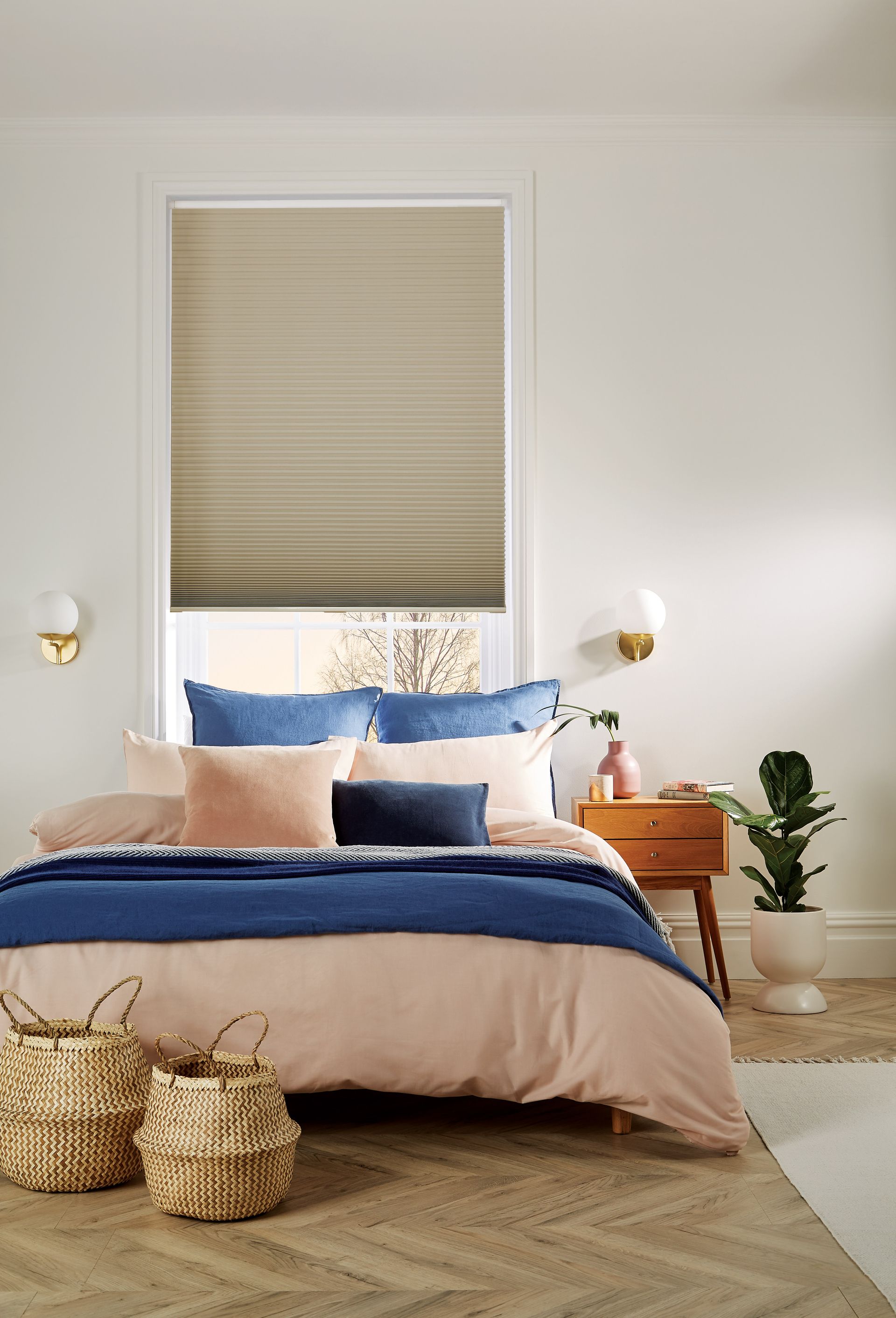 A bedroom with a bed , nightstand , baskets and a window.