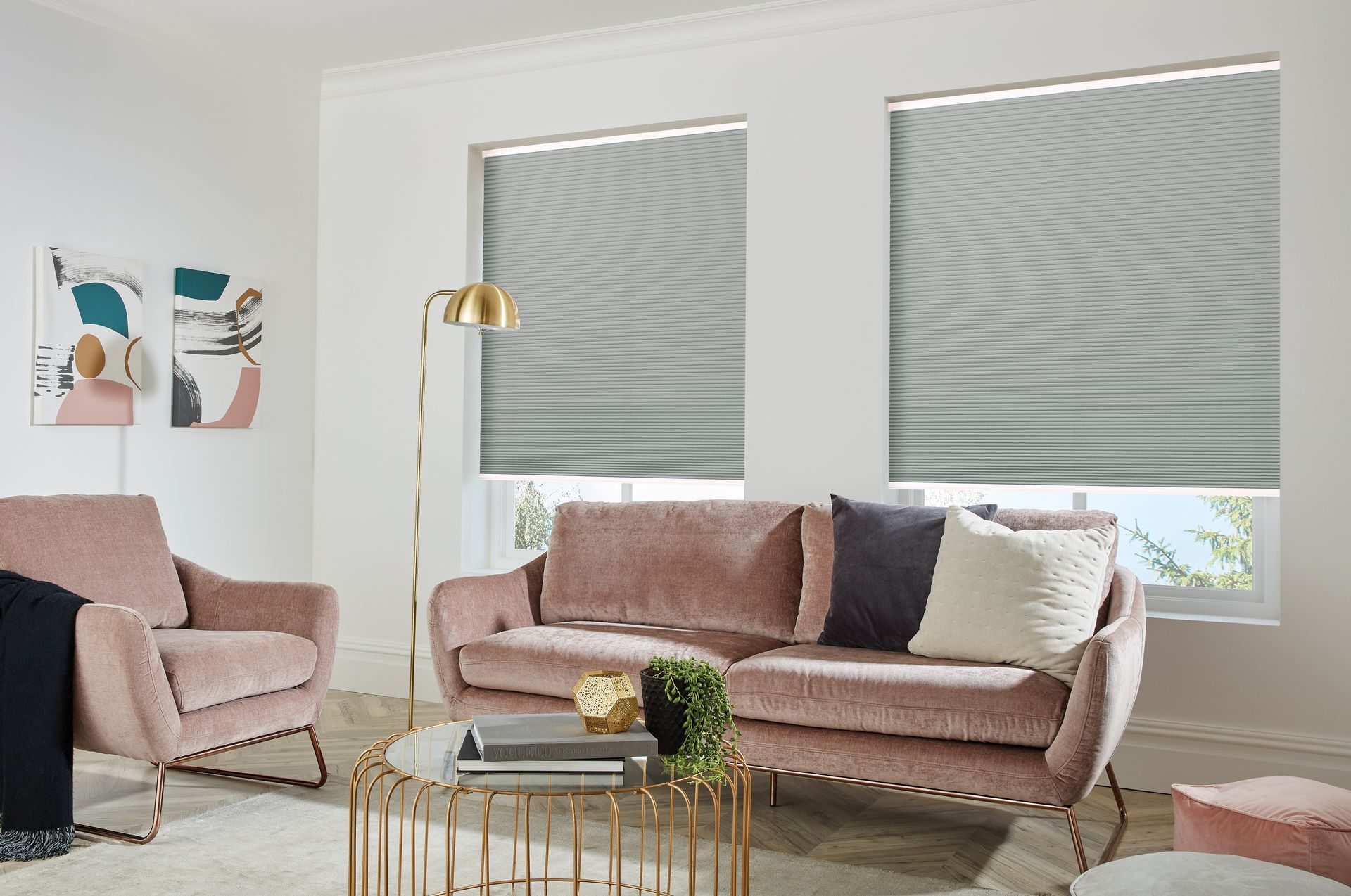 A living room with a pink couch , two chairs , and a coffee table.