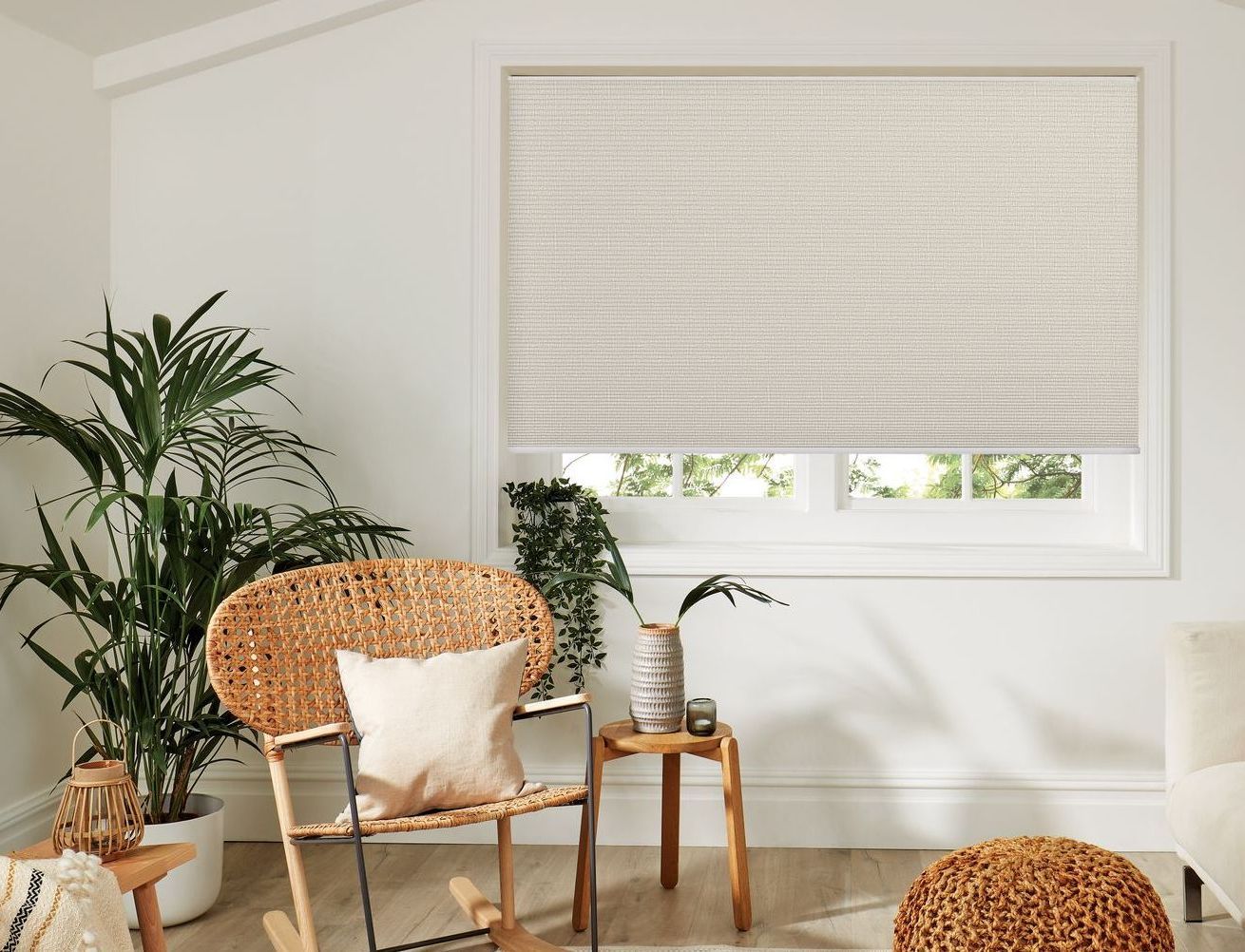 A living room with a rocking chair , table , and potted plants.