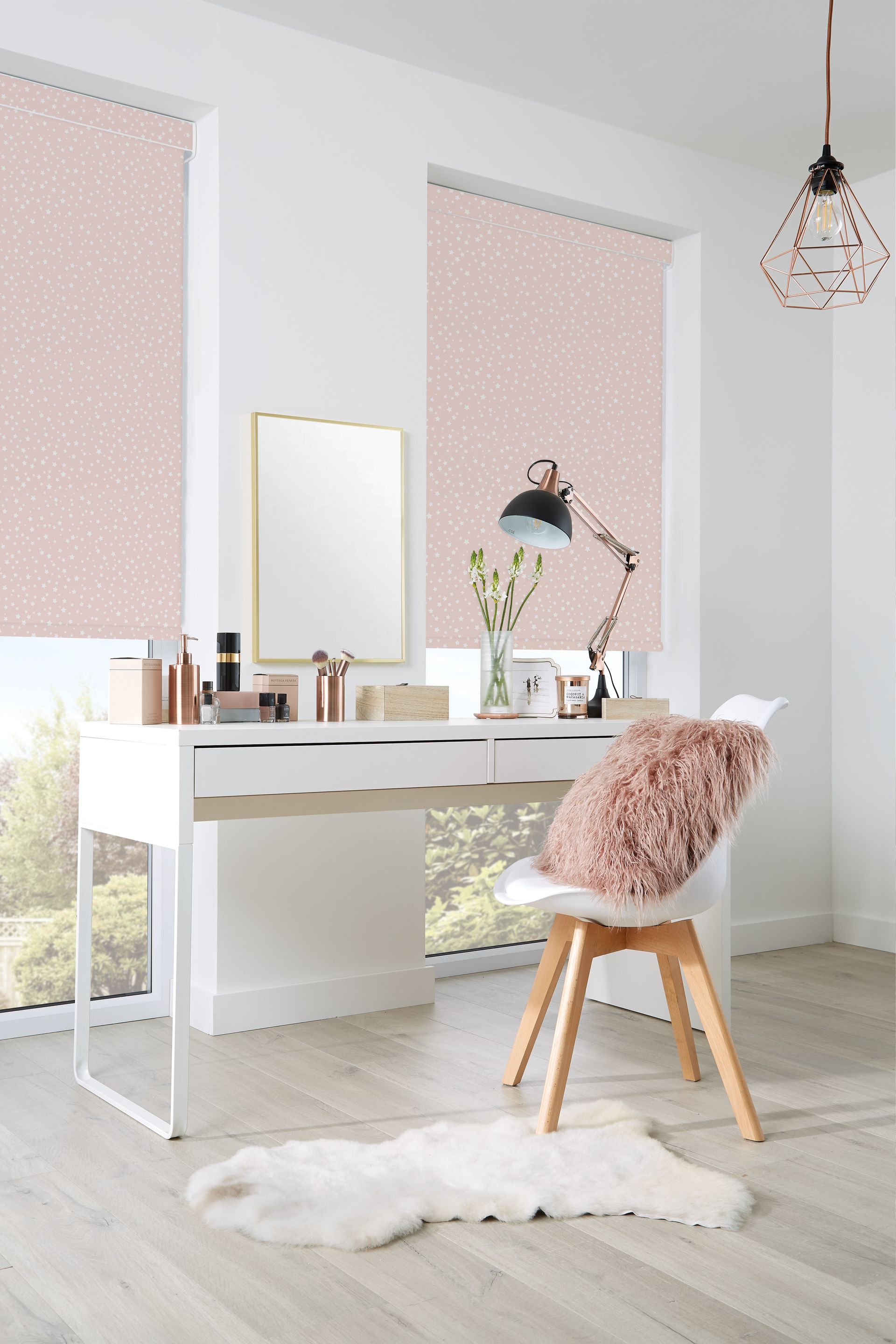 A bedroom with a desk , chair , mirror and pink blinds.