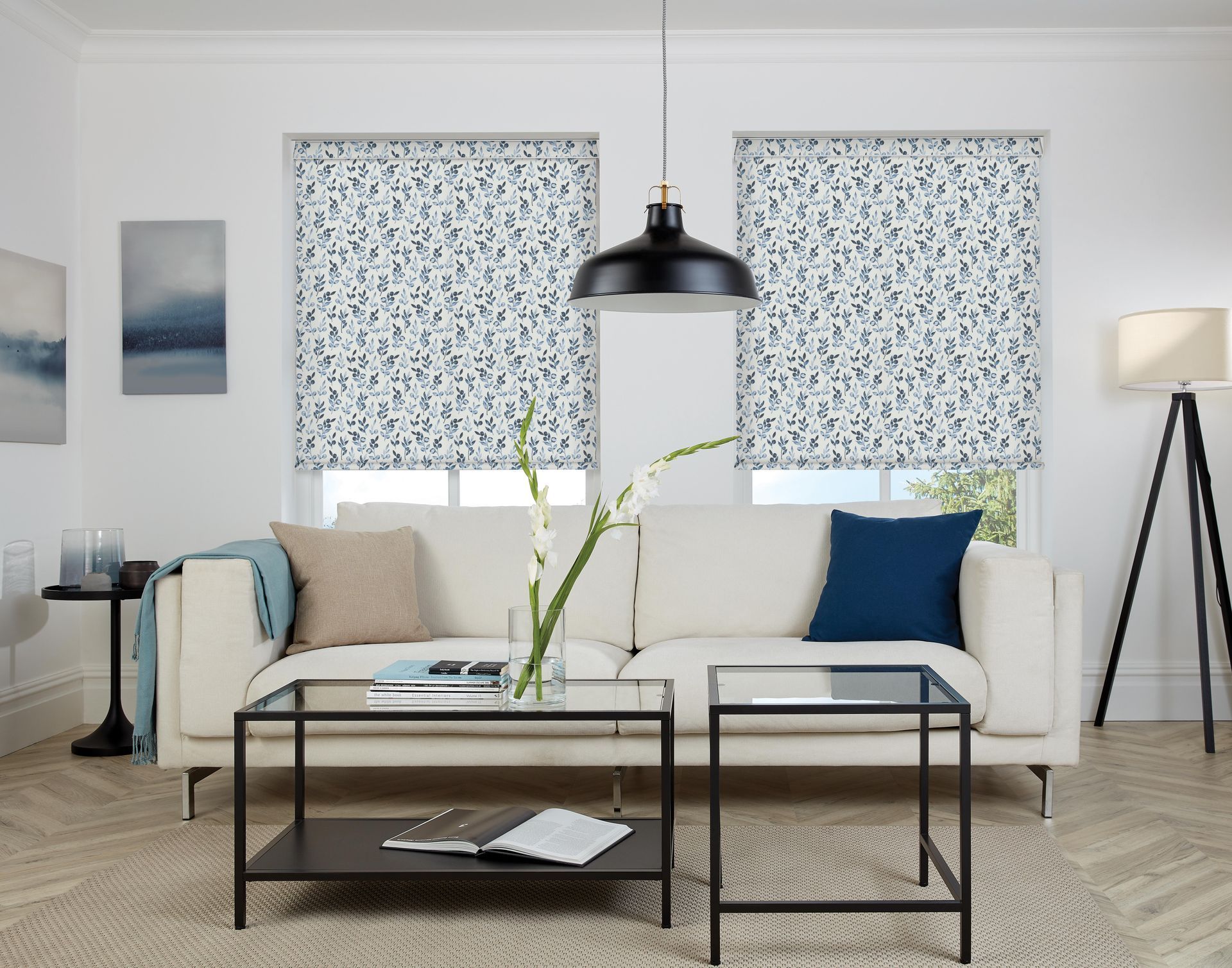 A living room with a white couch , two coffee tables , and a lamp.