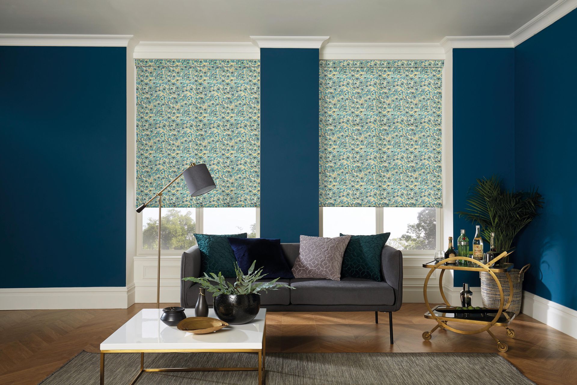 A living room with blue walls , a couch , a coffee table , and a bar cart.