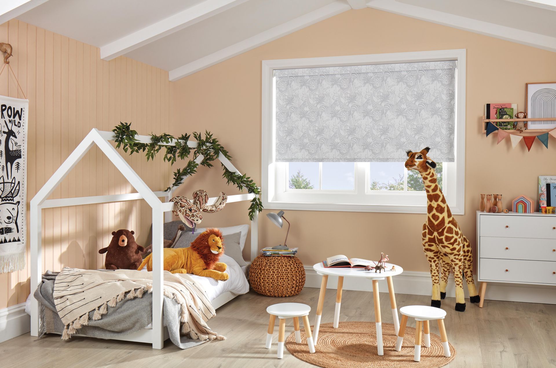 A child 's bedroom with a bed , table , and stuffed animals.