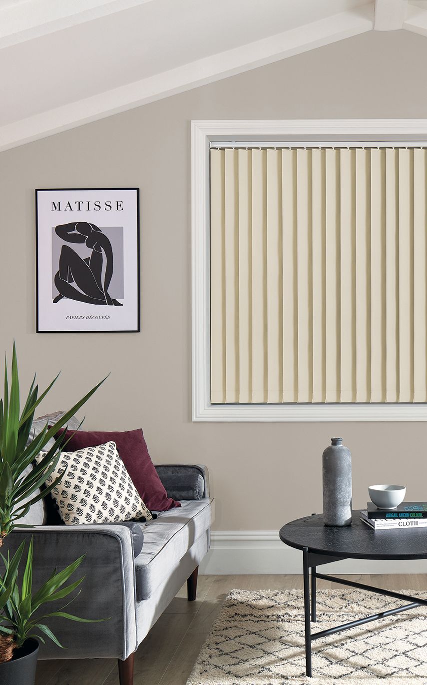 A living room with a couch , coffee table , and vertical blinds.