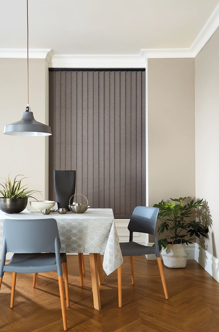 A dining room with a table and chairs and vertical blinds.