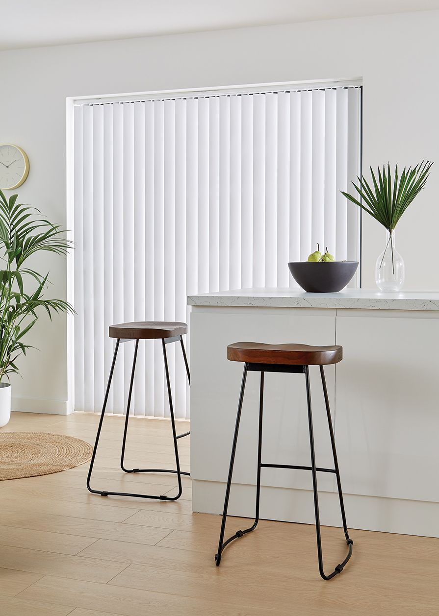 A kitchen with two bar stools and a bowl of fruit on the counter.