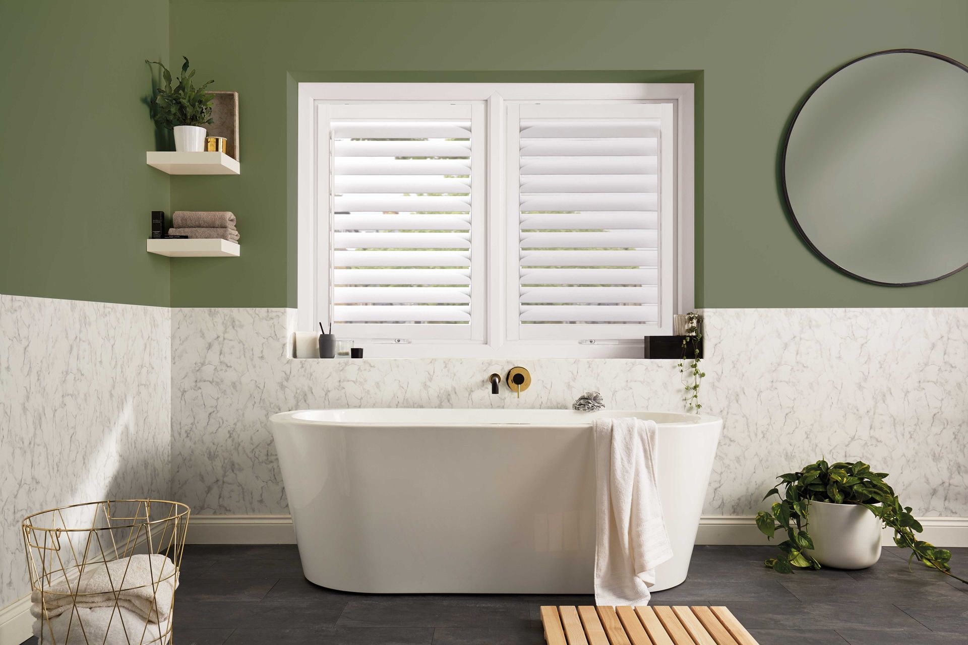 A bathroom with a bathtub , mirror , and shutters on the window.