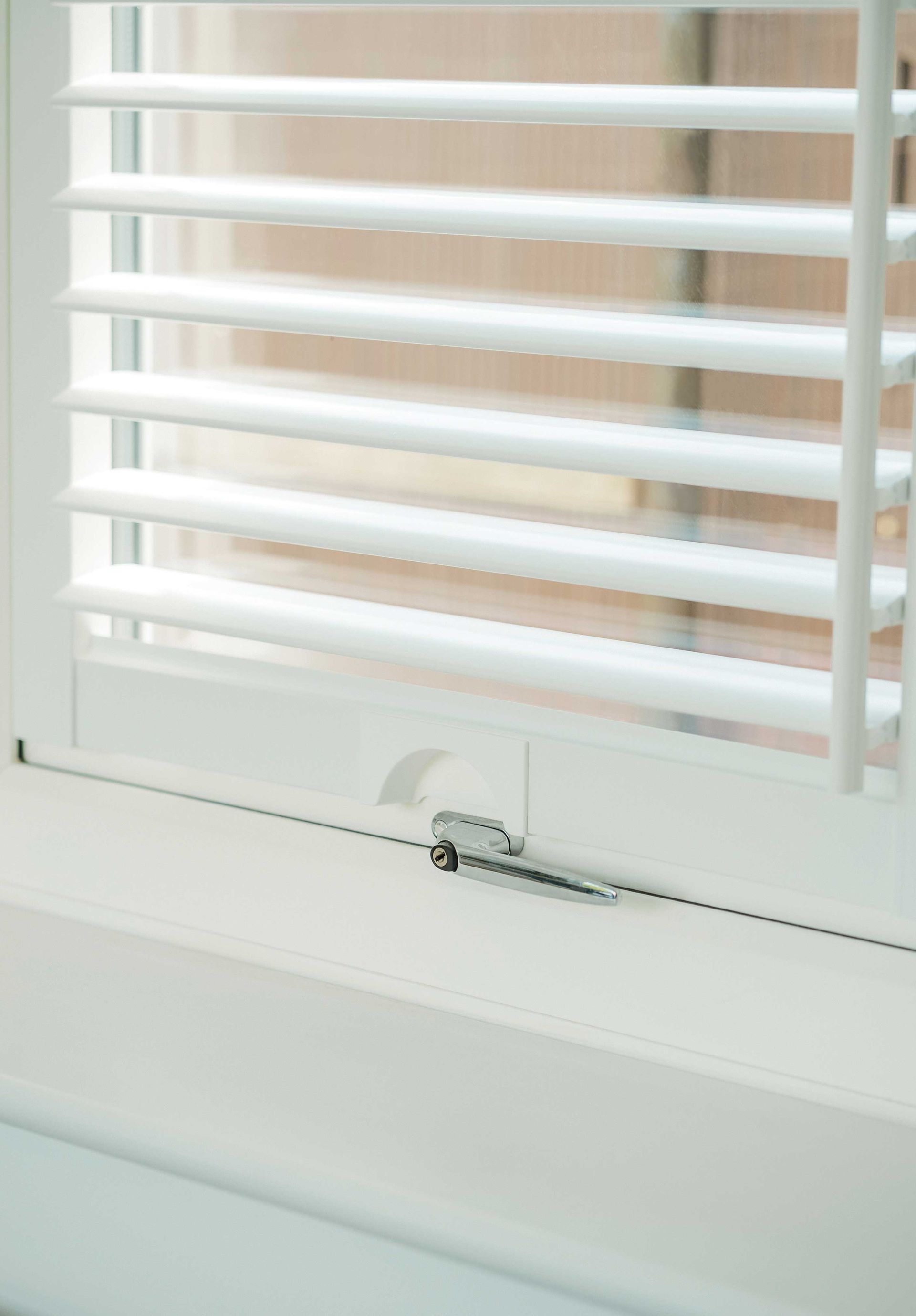 A close up of a window with white blinds on it.