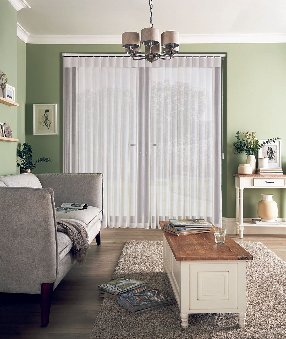 A living room with green walls and white vertical blinds