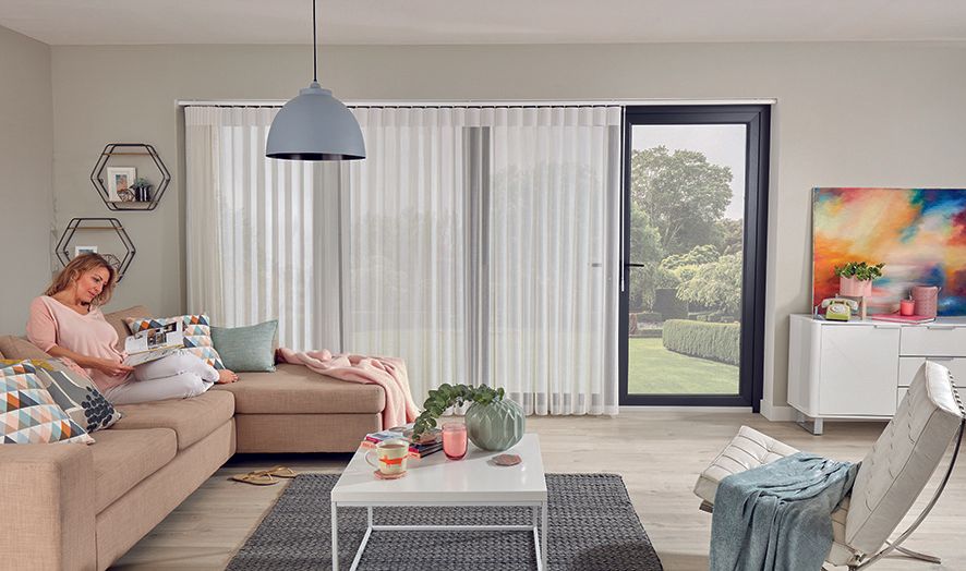A woman is sitting on a couch in a living room reading a book.