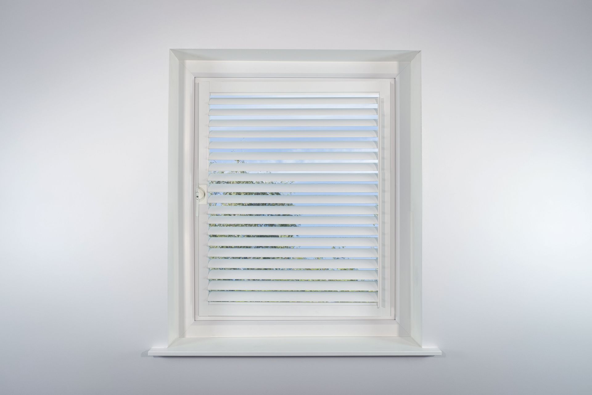 A window with blinds on it is against a white wall.