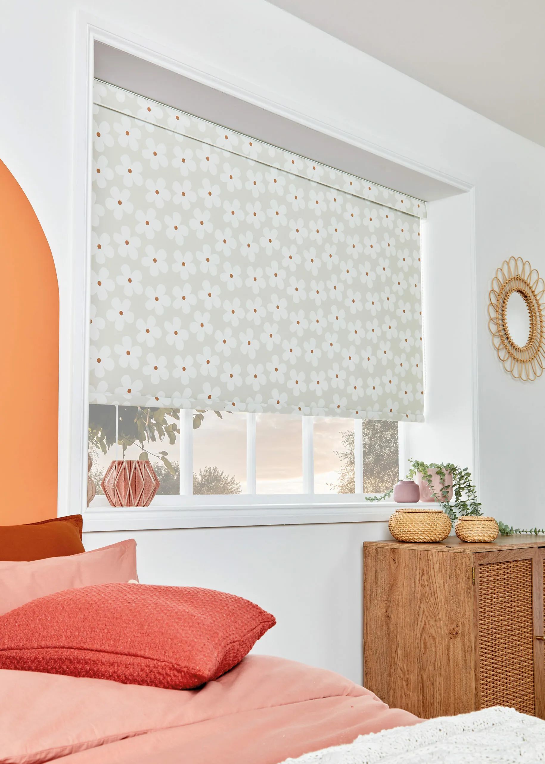 Bedroom with a closed, floral-patterned roller blind over a window. Features an orange arch, coral pillows, and wooden decor.