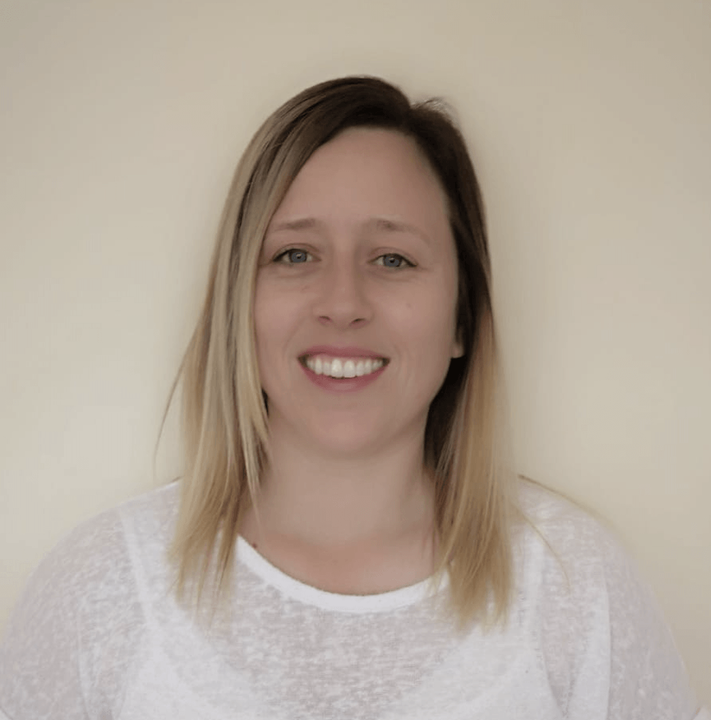 A woman in a white shirt is smiling for the camera