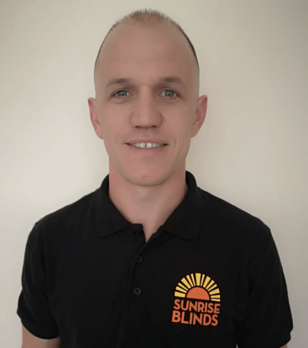 A man wearing a black shirt that says sunrise blinds