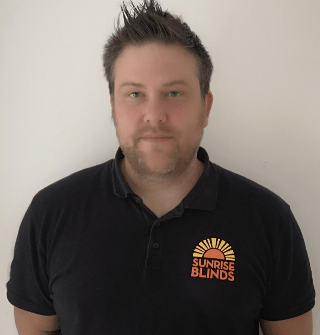 A man wearing a black shirt that says sunrise blinds
