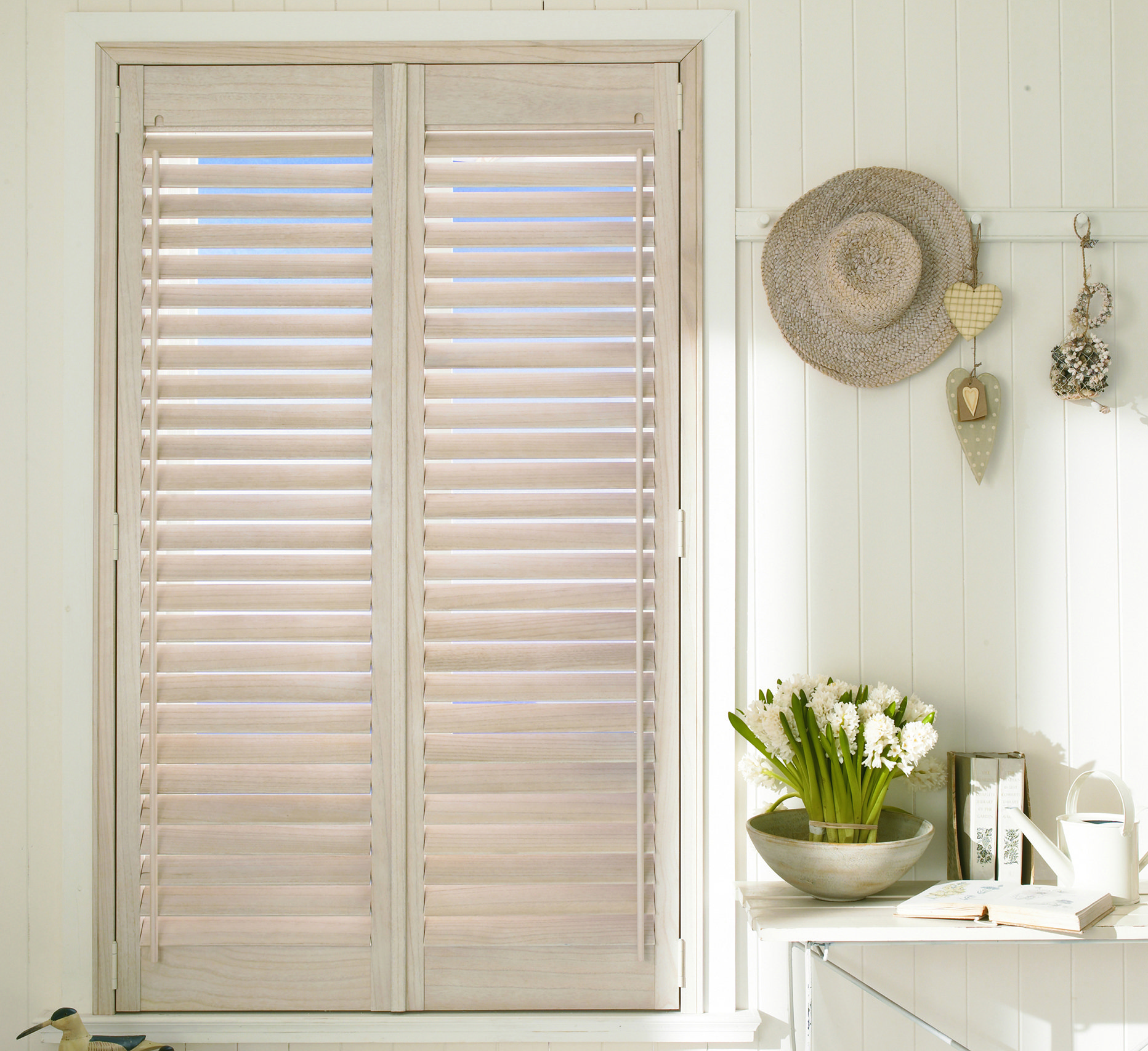A window with shutters and a vase of flowers on a table