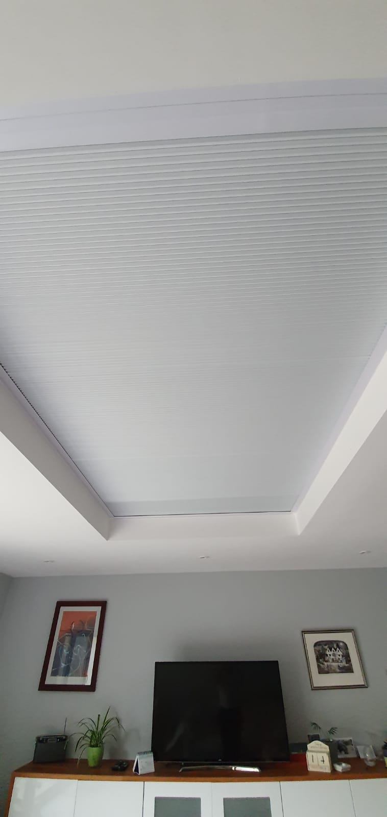 A living room with a flat screen tv and a white ceiling.