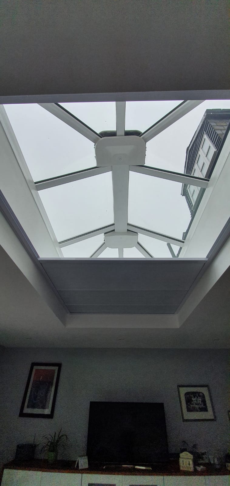 A living room with a skylight and a flat screen tv.