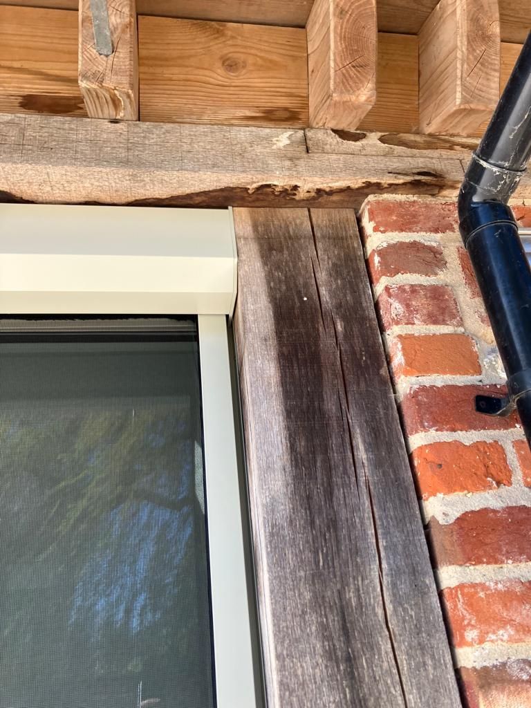 A brick wall with a window and a wooden beam.