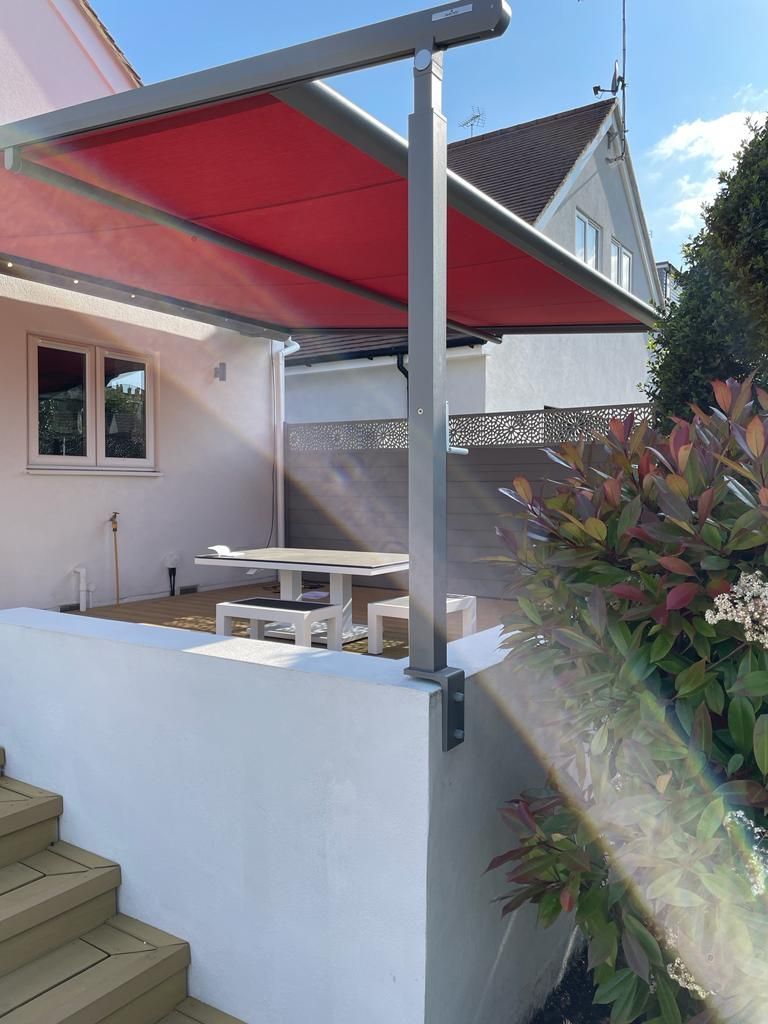 A red awning is covering a patio with a table and chairs.