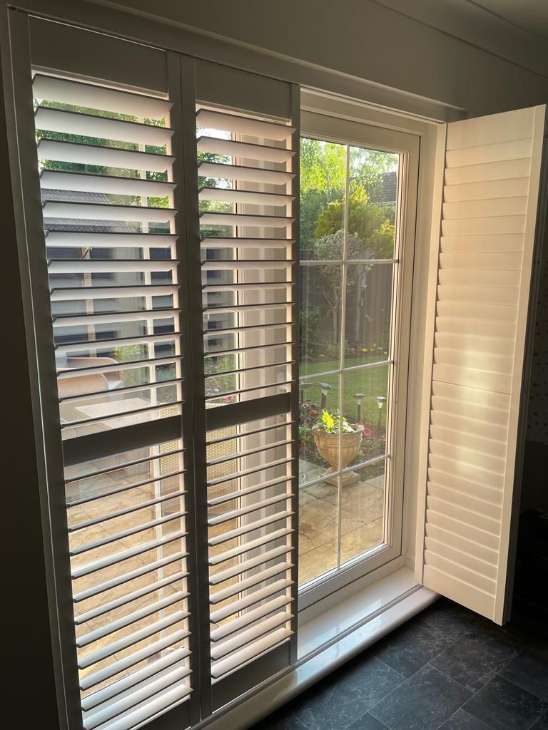 A sliding glass door with white shutters on it.