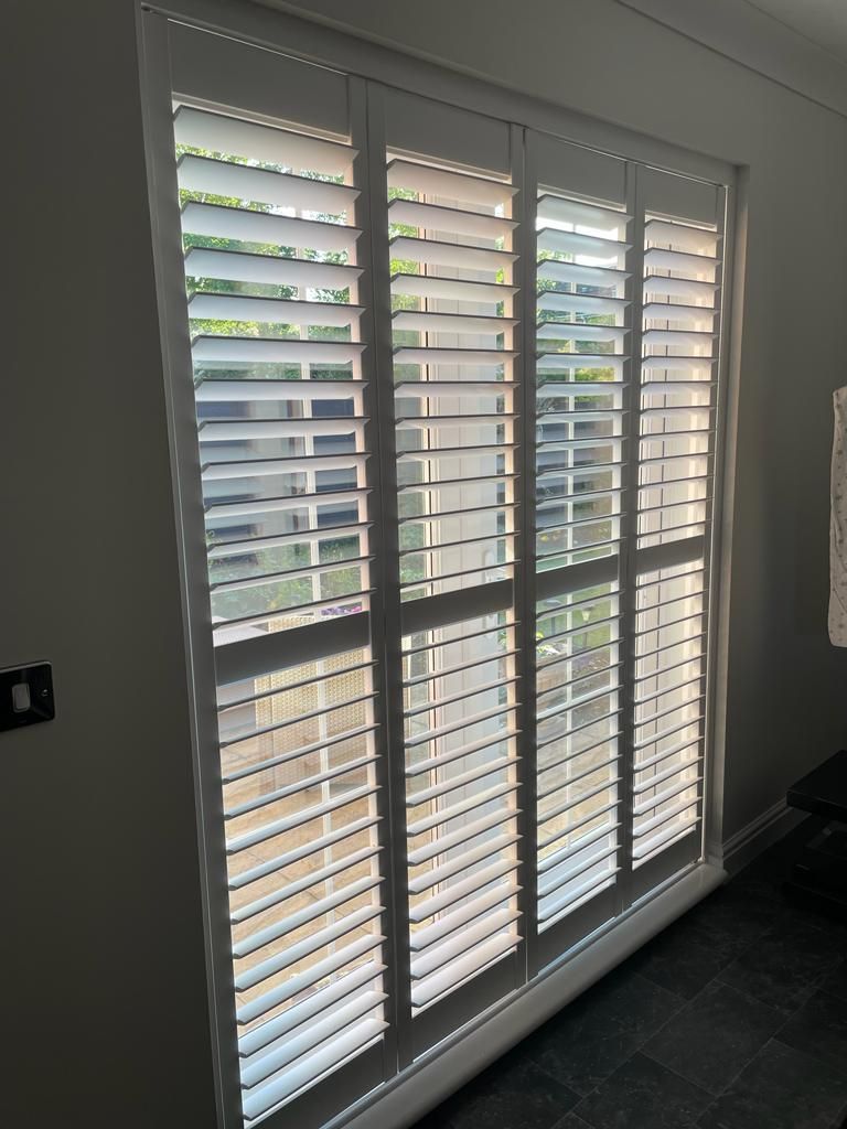 A sliding glass door with white shutters on it.
