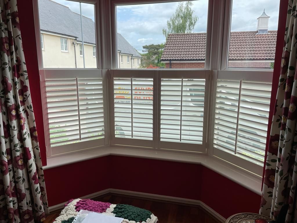 A room with a large window and shutters on it.