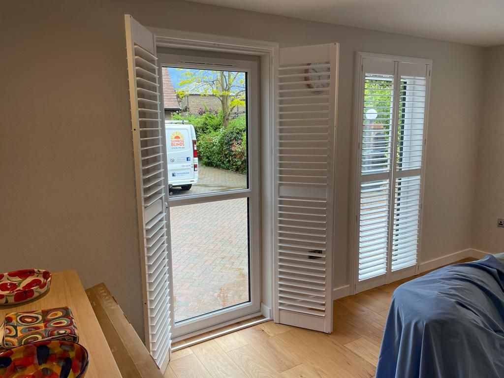 A bedroom with shutters on the windows and a bed.