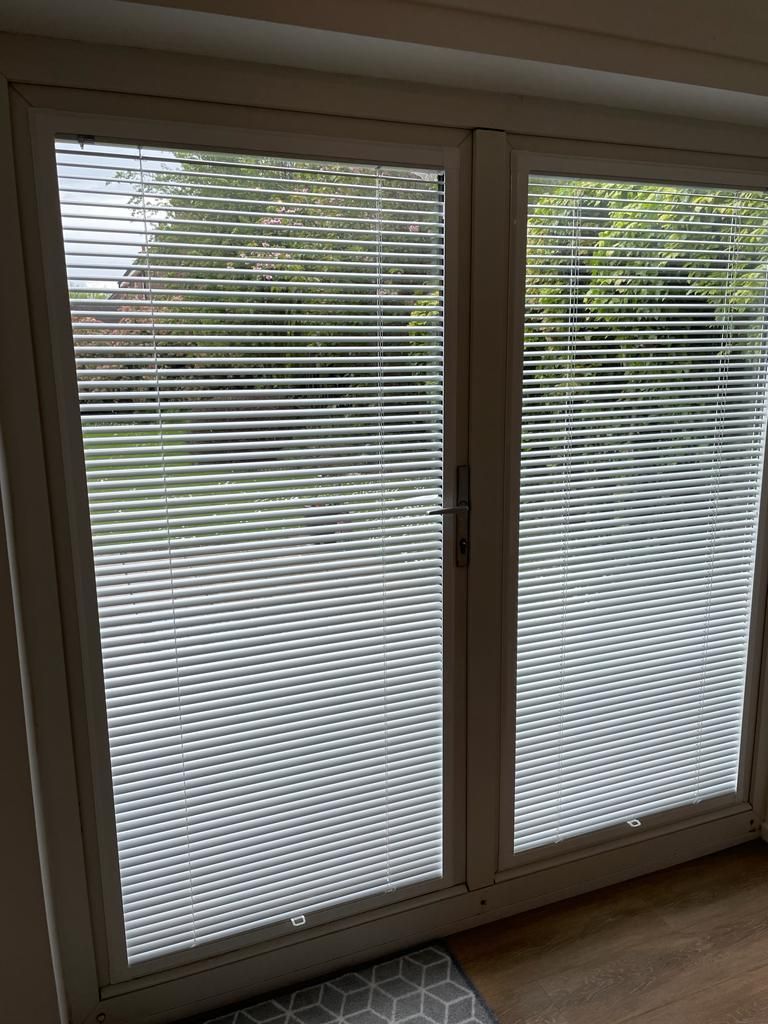 A pair of sliding glass doors with blinds on them.