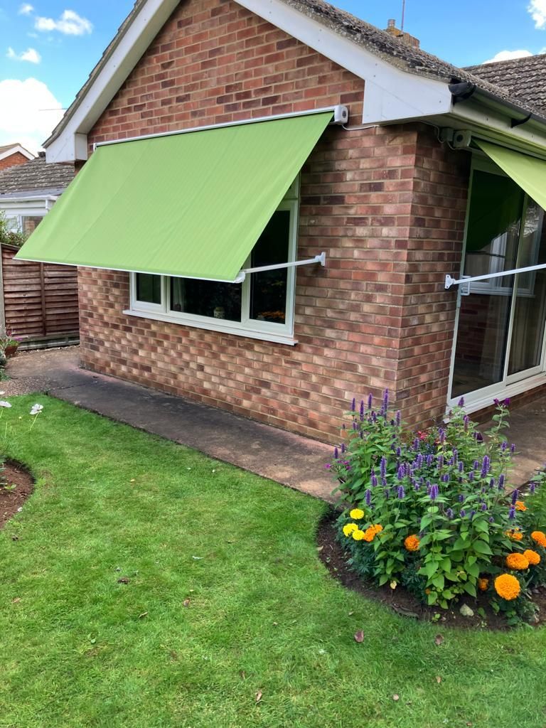 A brick house with a green awning over the window.