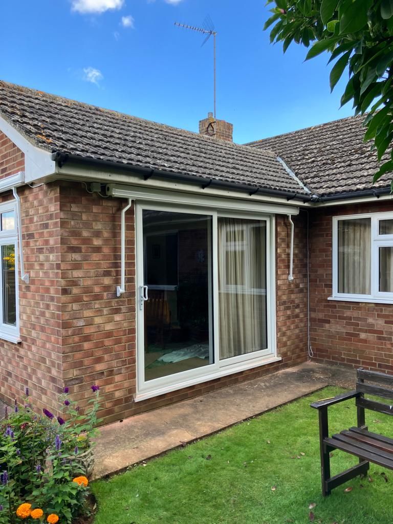 A brick house with sliding glass doors and a bench in front of it.