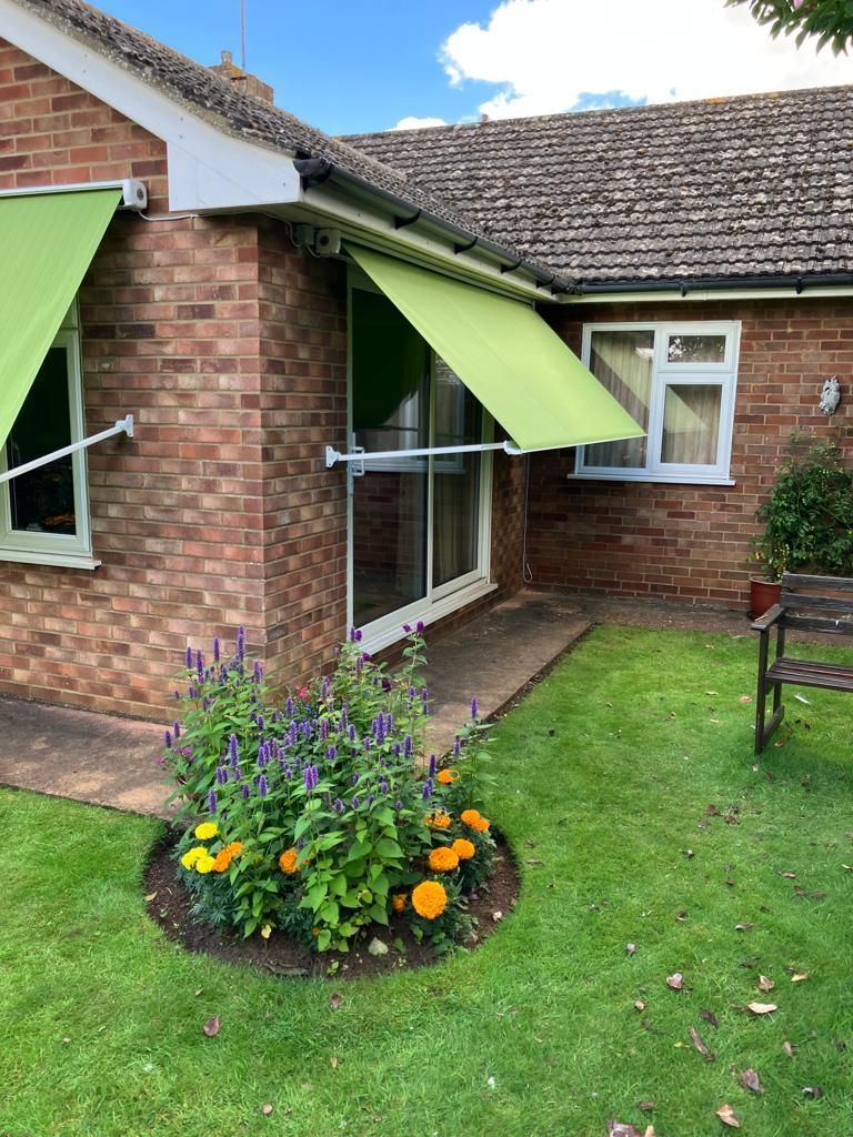 A brick house with a green awning on the side of it.