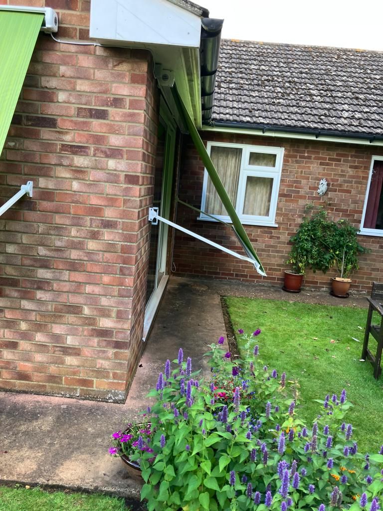 A brick house with a green awning on the side of it.
