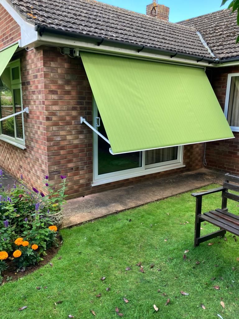 A house with a green awning on the side of it.