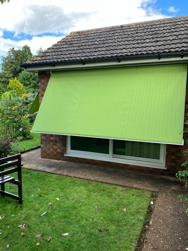 A green awning is hanging over a window of a house.