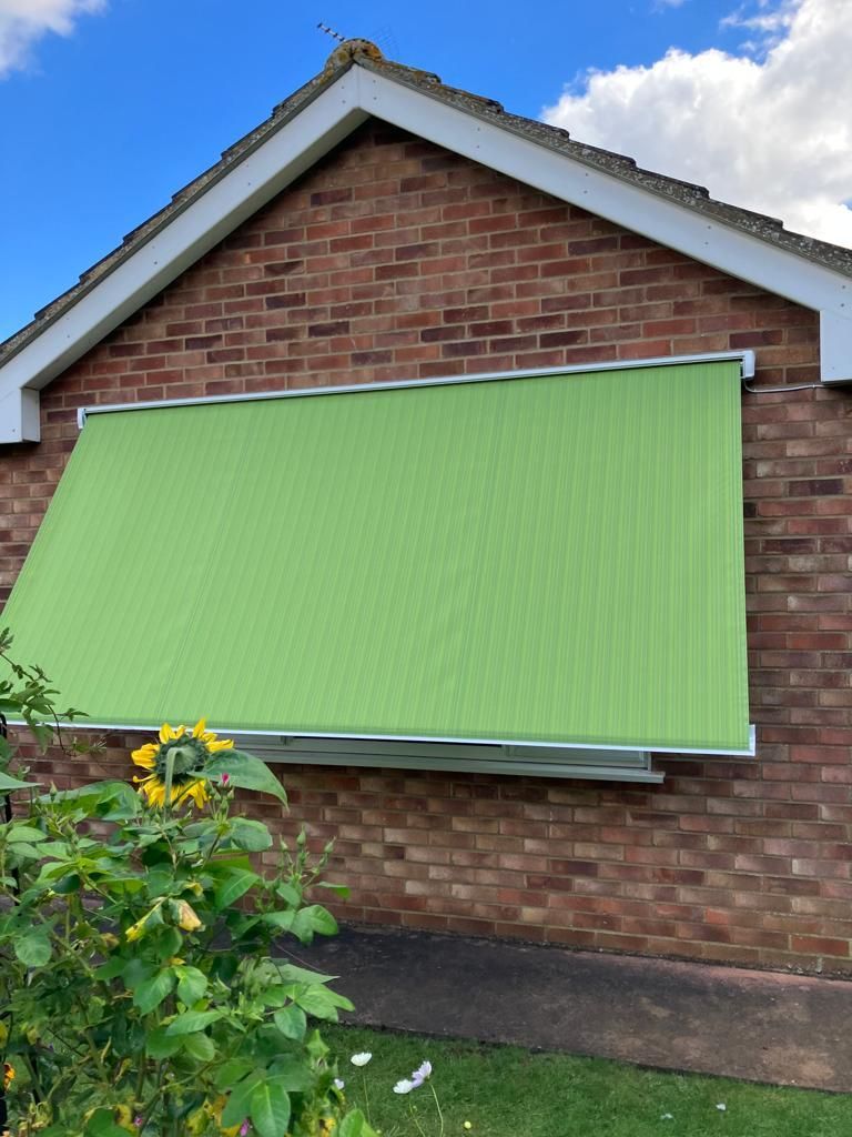 A green awning is on the side of a brick building