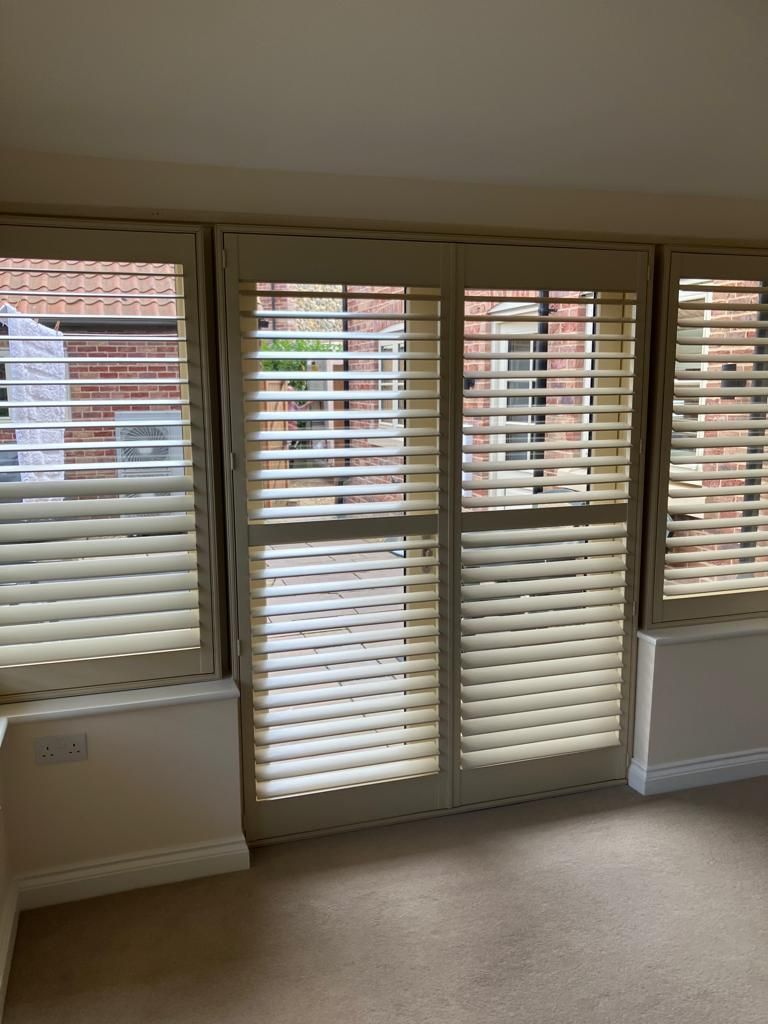 A room with a sliding glass door and shutters on the windows.