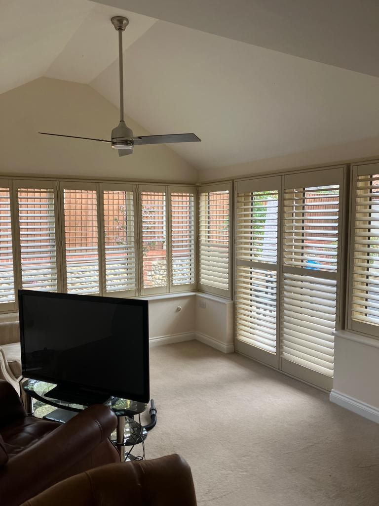 A living room with a flat screen tv and a ceiling fan.