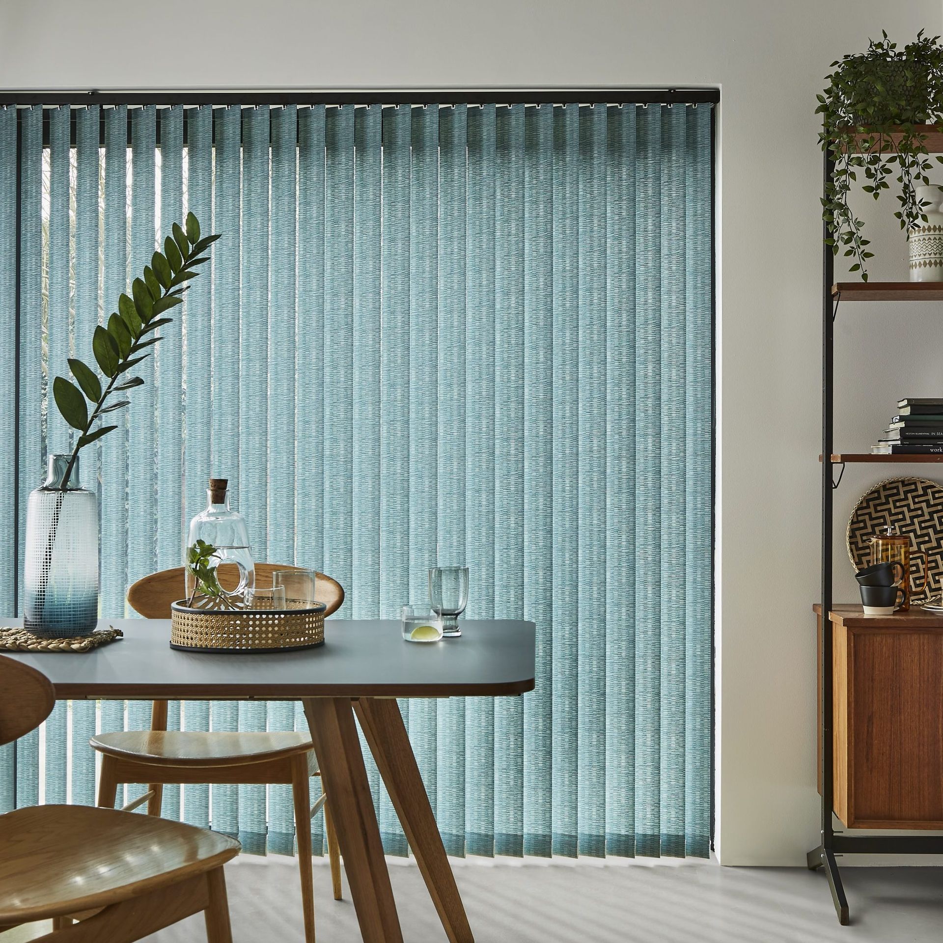 A dining room with a table and chairs and blue vertical blinds