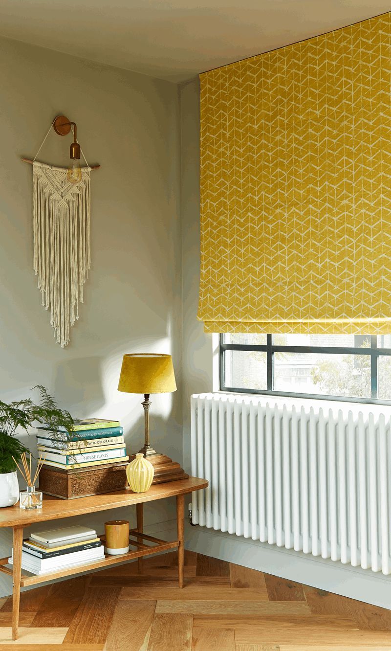 A living room with a table , lamp , and yellow blinds.