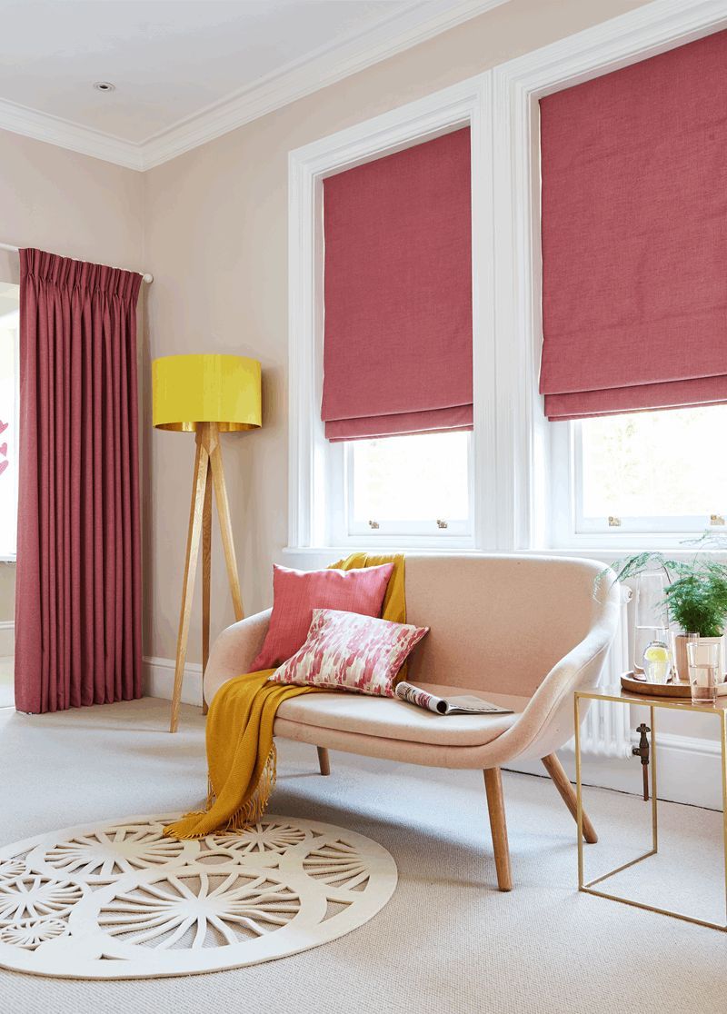 A living room with a couch , lamp , rug and pink blinds.