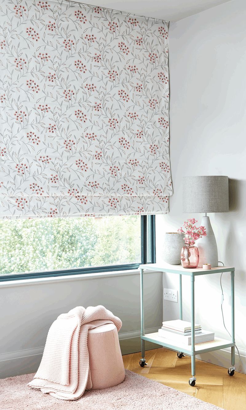 A bedroom with a floral roman blind on the window.
