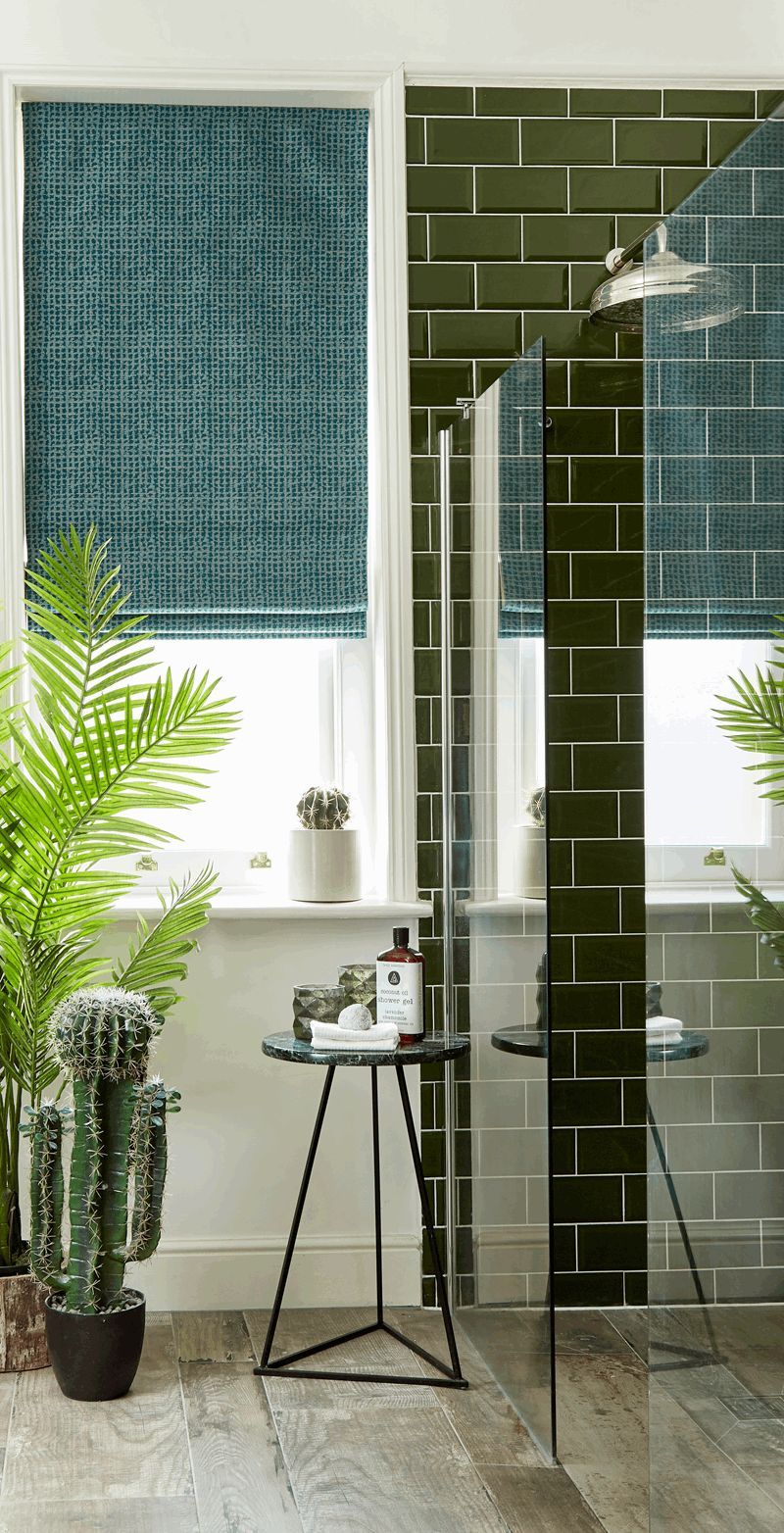 A bathroom with a walk in shower and a table with a cactus on it.