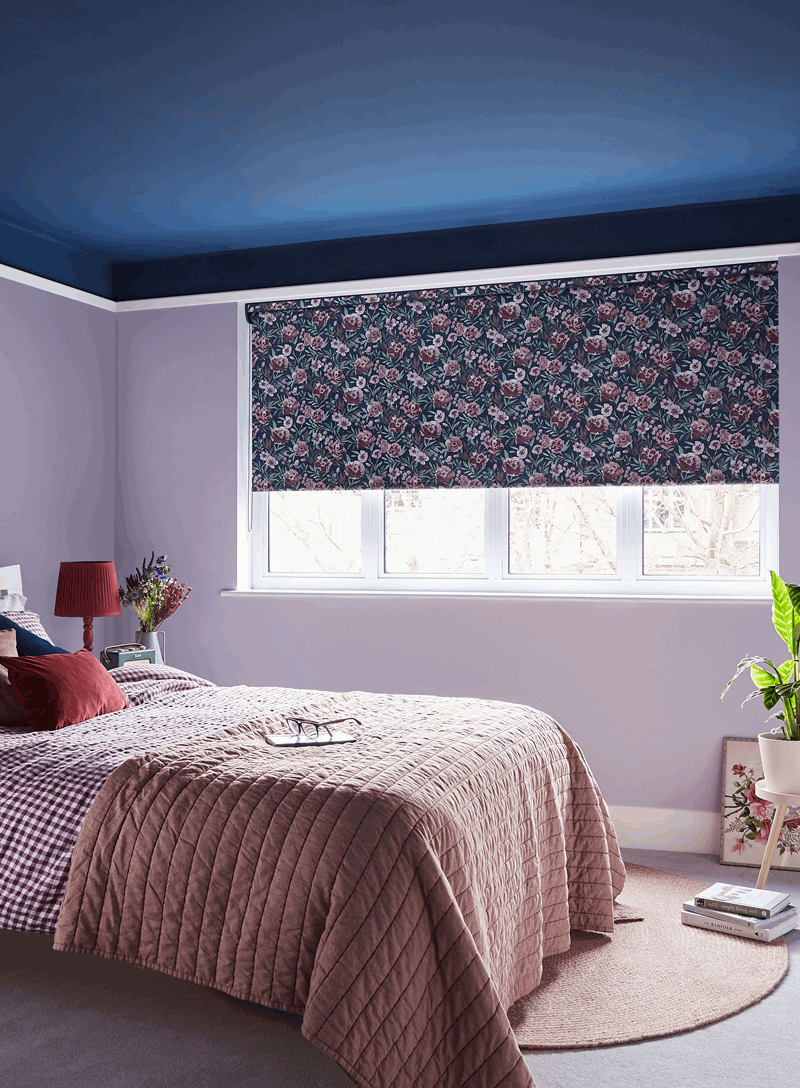 A bedroom with a bed , a window and a blue ceiling.