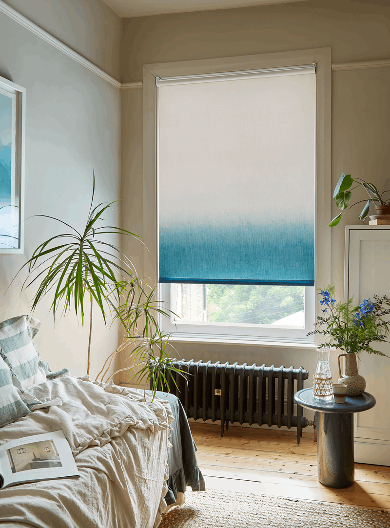 A bedroom with a bed , radiator , table and window.